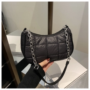 Détail d'un sac à bandoulière matelassé noir avec chaîne argentée et fermeture éclair