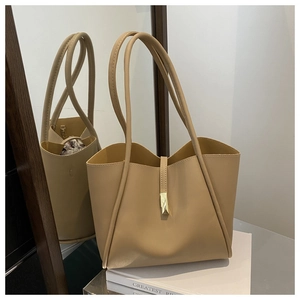 Dettaglio della borsa tote kaki minimalista con fibbia dorata su una scatola decorativa