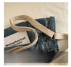 Détail du sac en velours bleu montrant la bandoulière large et la boucle en métal