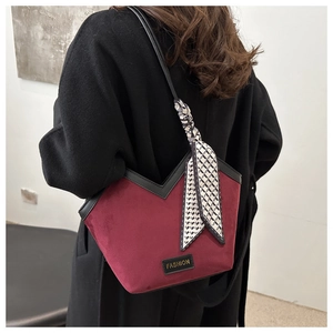 Detail of burgundy suede tote bag featuring a V-shaped cut and geometric scarf detail