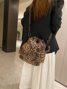 Detail of trendy leopard print bucket bag with adjustable shoulder strap on a model