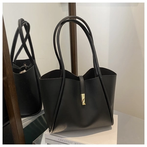 Dettaglio della borsa tote in pelle nera con fibbia dorata e tracolla sottile