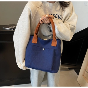 Détail du sac cabas bleu marine avec poignées orange et poche avant à boucle métallique