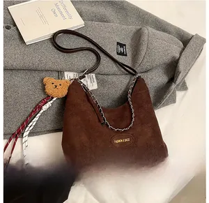 Détail du sac hobo en velours côtelé marron avec chaîne et breloque petit ourson