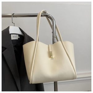 Dettaglio ravvicinato della borsa tote crema con elegante chiusura in metallo dorato