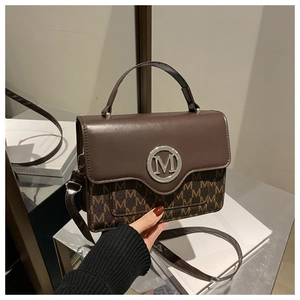 Detail of vintage square bag showing retro brown pattern and metallic silver M ring logo