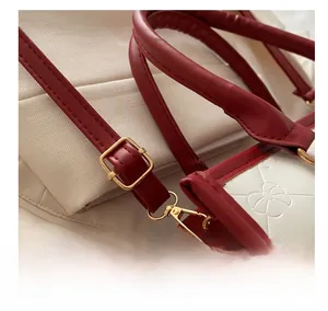 Close-up of red leather strap and golden metal buckle on contrast tote bag