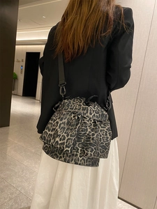 Close-up of leopard print canvas bucket bag with drawstring closure and adjustable strap