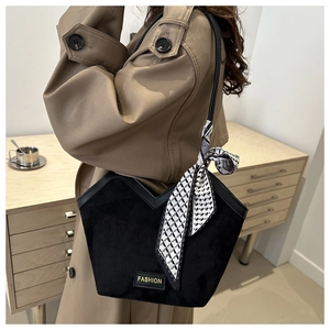 Close-up of black suede tote bag with FASHION label and geometric scarf on strap