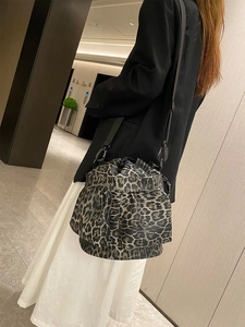 Side view of leopard print drawstring bucket bag worn by a model in a modern interior
