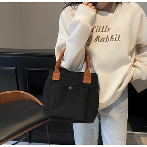 Détail du sac cabas noir en toile avec anses brunes et poche avant avec bouton pression