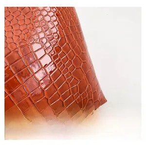 Macro shot of bright orange glossy faux leather with detailed crocodile skin texture