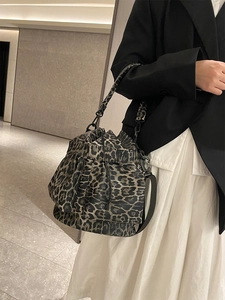Close-up of leopard print drawstring bucket bag with black leather straps and hardware