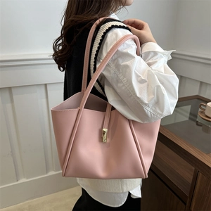 Borsa tote minimalista in pelle rosa con fibbia dorata indossata da una modella