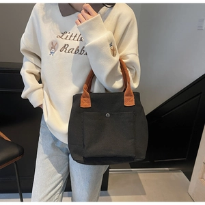 Détail du sac cabas en toile avec anses contrastées et poche à bouton-pression