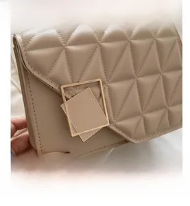 Détail d'un sac à bandoulière en cuir matelassé beige avec boucle dorée géométrique