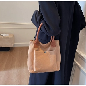 Détail d'un sac cabas en toile kaki avec poche frontale et poignées tressées rouge-brun