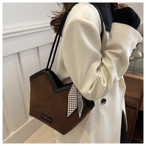 Detail of a dark brown suede tote bag featuring a V-shaped top and a polka dot scarf accessory