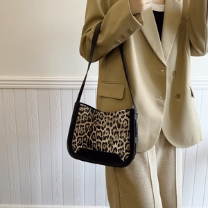 Vintage leopard print shoulder bag with black leather base shown on a beige blazer model