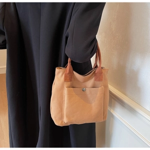 Détail du sac cabas en toile kaki avec poche avant et bouton-pression en argent poli
