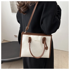 Detail of contrast color tote bag with bow texture pattern and adjustable shoulder strap