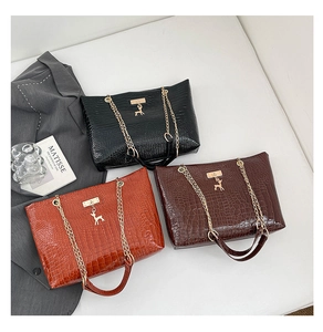 Detail view of crocodile-patterned tote bags with gold chain straps and deer charms