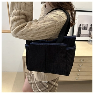 Détail du sac cabas en velours côtelé montrant la poche latérale et la texture sur le modèle