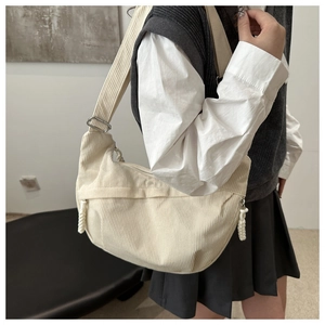 Détail du sac croissant en velours côtelé blanc cassé avec bandoulière large réglable
