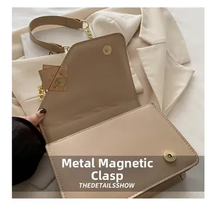Détail de la fermeture magnétique en métal sur un sac à bandoulière minimaliste beige clair