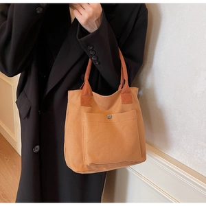 Vue détaillée du sac cabas en toile marron caramel avec poche avant et bouton métallique