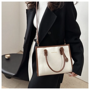 Close-up of contrast color tote bag with bow-knot embossing and golden fashion logo text