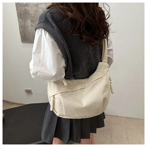 Détail du sac croissant en velours côtelé blanc cassé avec rayures et sangle réglable