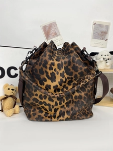 Detail view of leopard print bucket bag with drawstring closure and brown strap