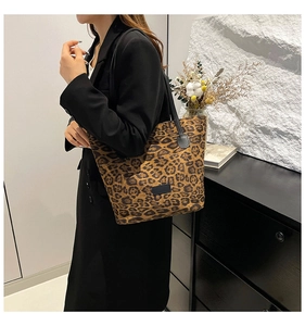 Detailed view of leopard print canvas tote bag with leather strap on a model