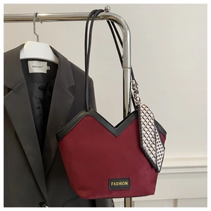 Detail of burgundy suede tote with V-cut opening and a decorative geometric silk scarf