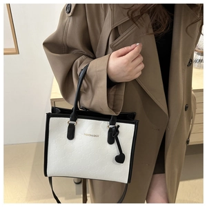Detail of contrast stitching tote bag with bow embossing and heart charm on a trench coat