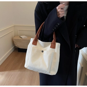 Détail du sac cabas en toile avec anses marron et poche extérieure à bouton-pression argenté