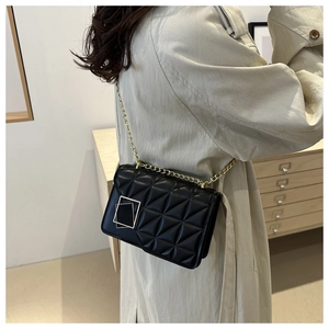 Vue détaillée du sac à bandoulière matelassé noir avec chaîne dorée porté par un mannequin
