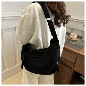 Mannequin portant un grand sac bandoulière en velours côtelé noir au style minimaliste