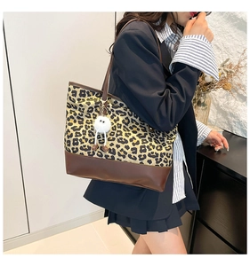Dettaglio della grande borsa tote leopardata con manici in ecopelle marrone e ciondolo