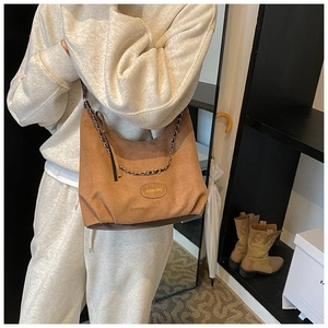 Sac bandoulière en daim marron avec chaîne dorée et détail logo cuir sur modèle
