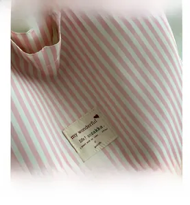 Detail of the pink and white striped fabric texture and woven label on a large tote bag