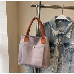 Détail du sac cabas en toile gris-violet avec poignées orange-brun et poche à bouton pression