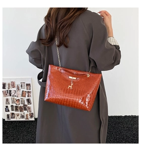 Orange croc-effect shoulder bag with gold deer charm shown on model back view