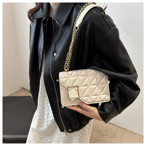 Détail d'un sac à bandoulière matelassé beige avec chaîne dorée et boucle carrée élégante