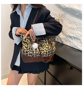 Dettaglio della borsa tote leopardata con cinturini in pelle marrone e ciondolo peluche