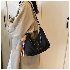 Sac hobo chic en toile noire avec chaîne argentée et breloque ours porté par mannequin