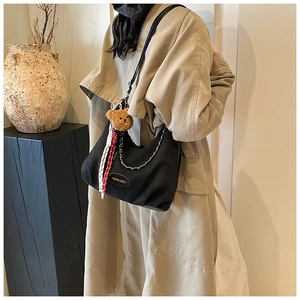 Détail du sac demi-lune en toile noire avec chaîne argentée et breloque ours en peluche