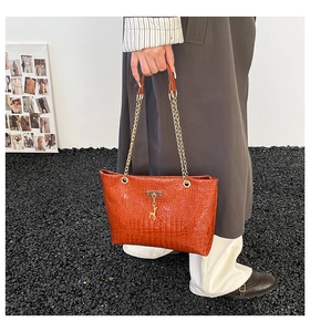 Orange crocodile texture tote bag detail with golden deer pendant and chain strap