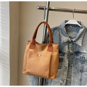 Détail du sac cabas en toile montrant la poche extérieure avec bouton pression en métal argenté